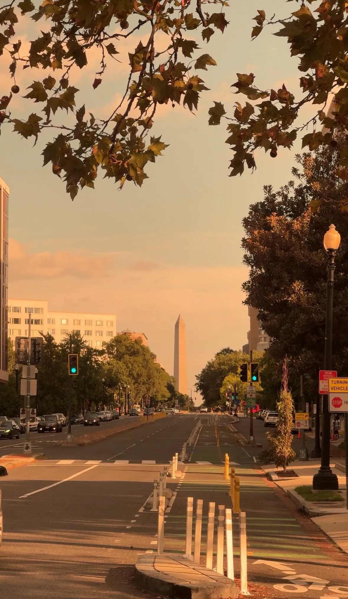 A wide avenue at golden hour, the Washington Monument in the distance.