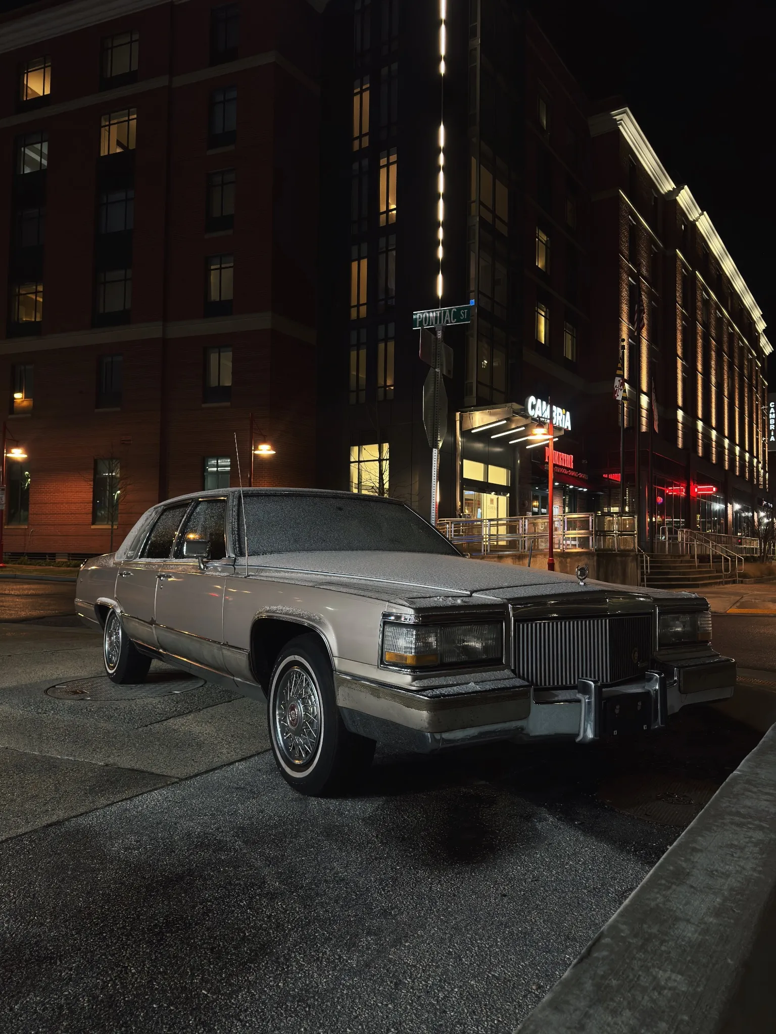 A vintage Cadillac sedan parked on a city street at night.